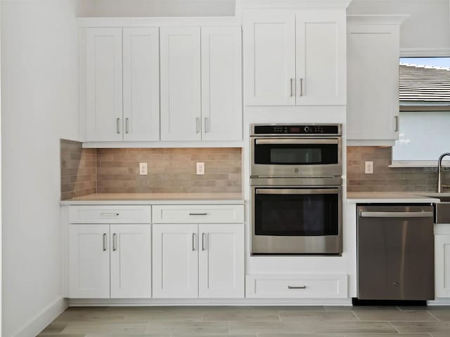 kitchen featuring white cabinetry, stainless steel appliances, and backsplash