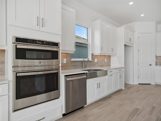 kitchen featuring stainless steel appliances, white cabinetry, sink, and tasteful backsplash