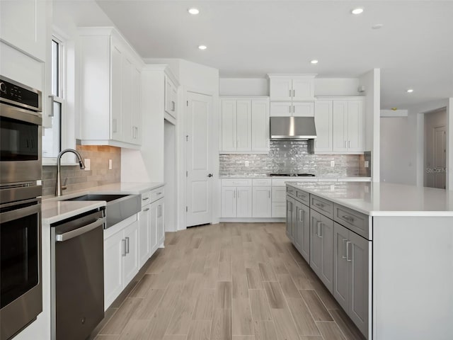 kitchen with gray cabinets, appliances with stainless steel finishes, sink, white cabinets, and light wood-type flooring