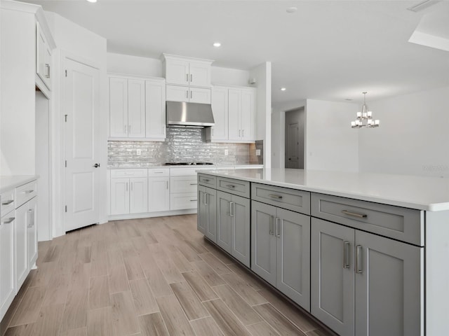 kitchen featuring tasteful backsplash, gray cabinets, light hardwood / wood-style floors, and white cabinets