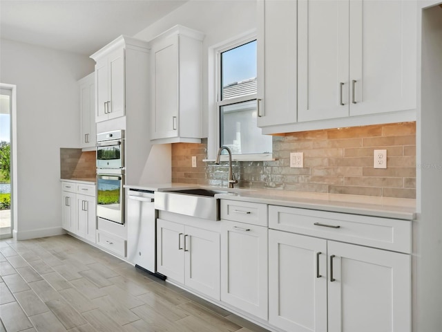 kitchen featuring sink, white cabinetry, tasteful backsplash, appliances with stainless steel finishes, and a healthy amount of sunlight