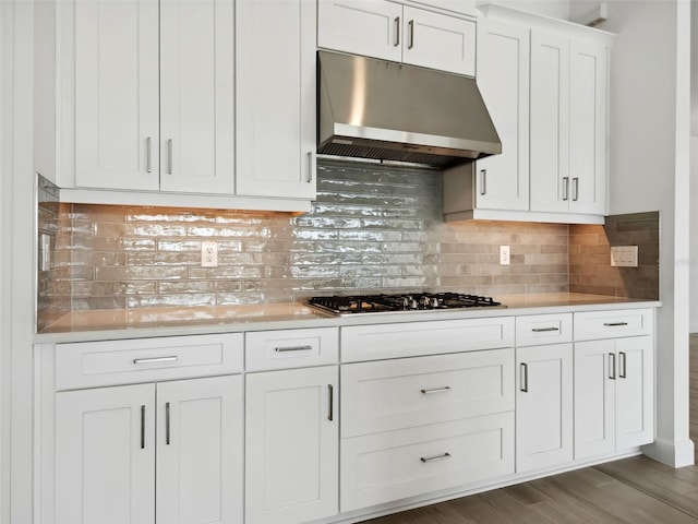 kitchen featuring hardwood / wood-style flooring, stainless steel gas cooktop, decorative backsplash, and white cabinets