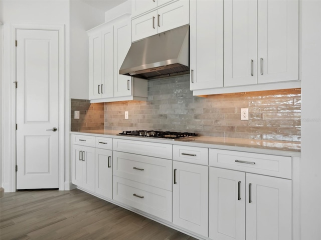 kitchen with tasteful backsplash, stainless steel gas cooktop, white cabinets, and light hardwood / wood-style flooring