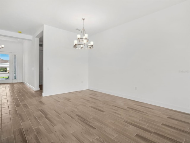 unfurnished room with a chandelier and light hardwood / wood-style flooring