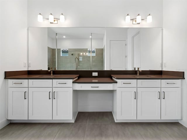 bathroom featuring tile patterned flooring, vanity, and a tile shower