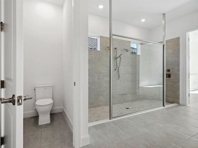 bathroom featuring tile patterned floors, toilet, and tiled shower