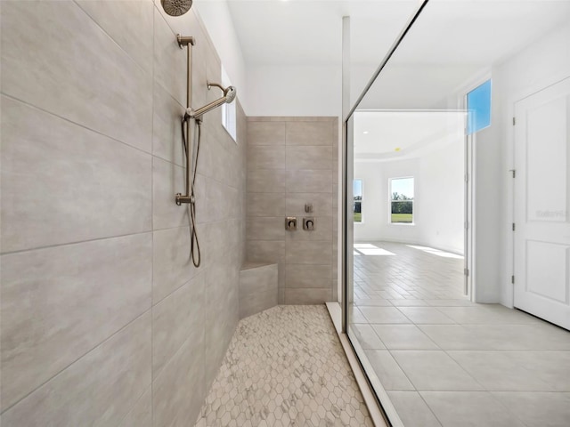 bathroom with a tile shower and tile patterned flooring