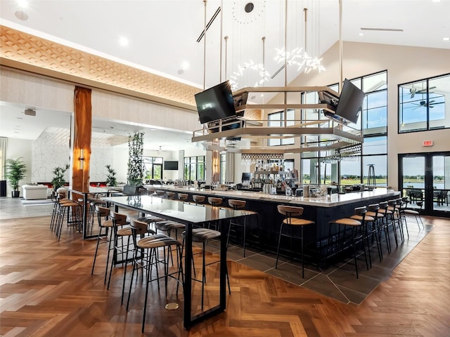 bar featuring hanging light fixtures, dark parquet floors, french doors, and a high ceiling