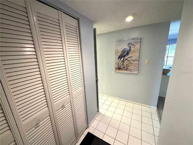 hall with light tile patterned flooring and a textured ceiling