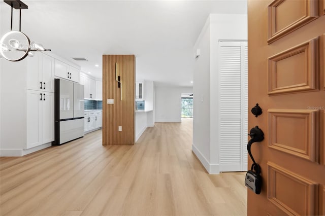 kitchen with visible vents, freestanding refrigerator, light wood-style floors, white cabinetry, and pendant lighting