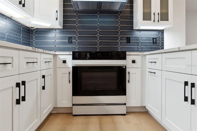 kitchen featuring black electric range oven, white cabinets, and light wood-type flooring