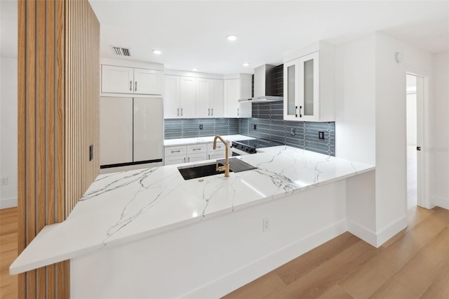 kitchen with light stone countertops, white cabinetry, white fridge, and kitchen peninsula