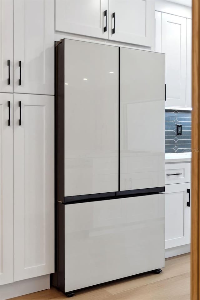 interior space featuring white cabinetry, backsplash, fridge, and light hardwood / wood-style floors