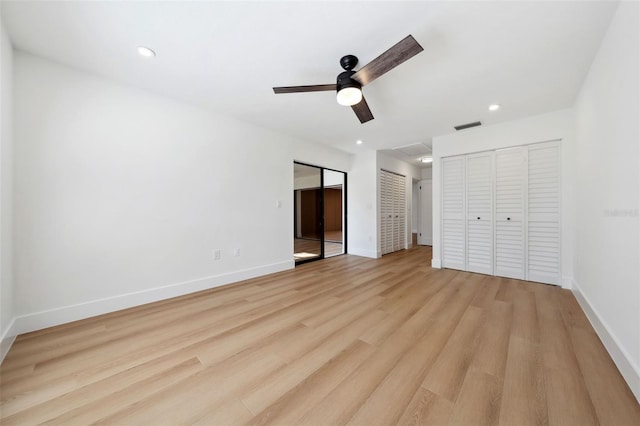 unfurnished bedroom featuring ceiling fan, two closets, and light hardwood / wood-style floors