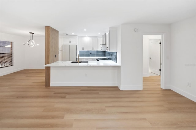 kitchen with refrigerator, white cabinetry, hanging light fixtures, light hardwood / wood-style floors, and kitchen peninsula