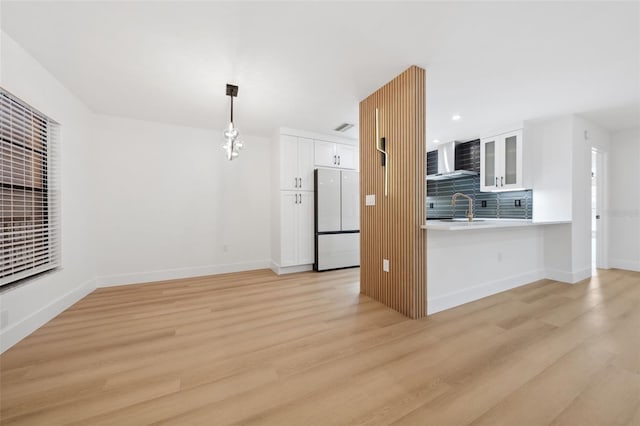 kitchen featuring sink, white fridge, white cabinets, kitchen peninsula, and light wood-type flooring