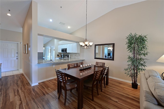 dining room with a notable chandelier, vaulted ceiling, and dark hardwood / wood-style floors