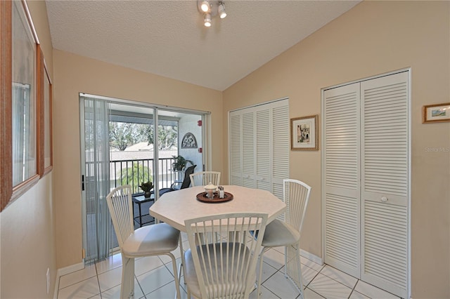 tiled dining room with vaulted ceiling and a textured ceiling