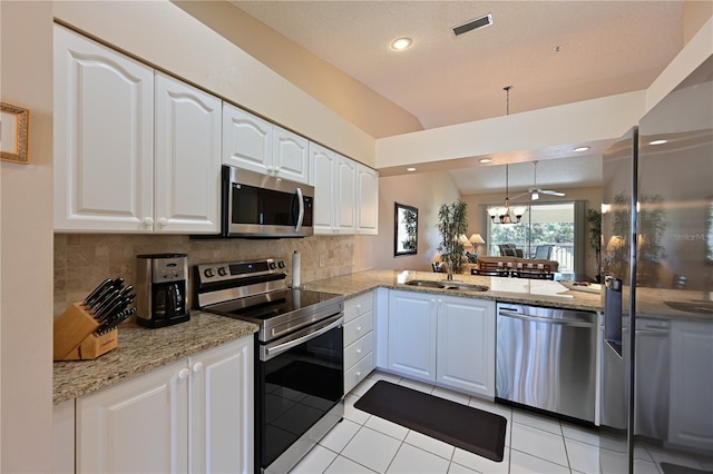 kitchen featuring appliances with stainless steel finishes, backsplash, white cabinets, decorative light fixtures, and kitchen peninsula