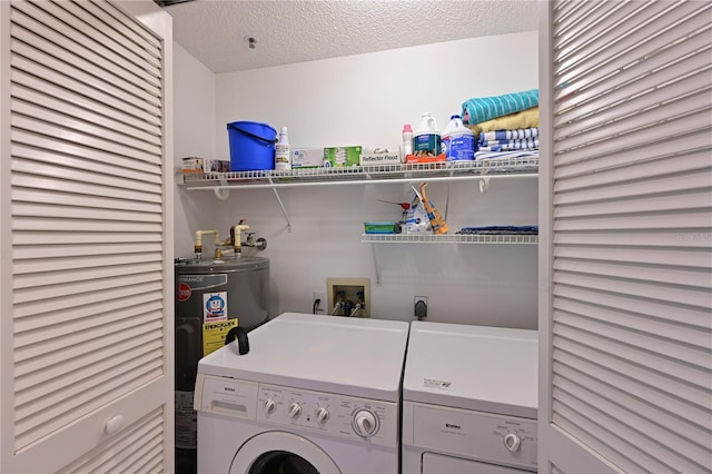 clothes washing area featuring independent washer and dryer, water heater, and a textured ceiling