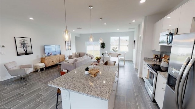 kitchen with sink, a breakfast bar area, decorative light fixtures, stainless steel appliances, and white cabinets