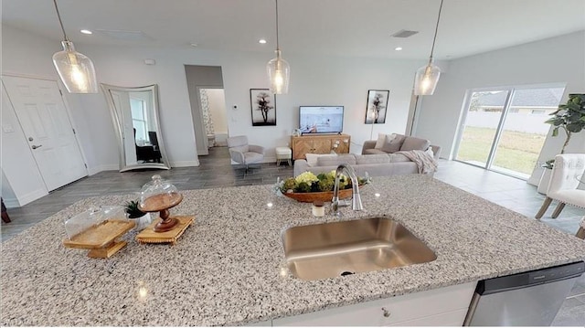 kitchen featuring light stone countertops, sink, and hanging light fixtures