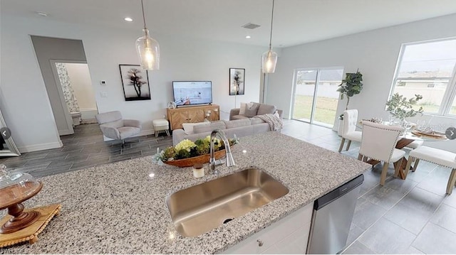 kitchen with pendant lighting, sink, and light stone counters