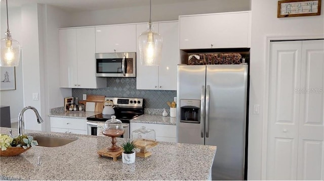 kitchen featuring white cabinetry, stainless steel appliances, sink, and hanging light fixtures