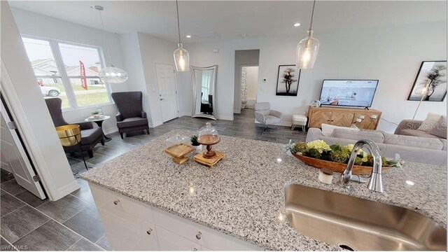 kitchen featuring white cabinetry, light stone countertops, sink, and decorative light fixtures