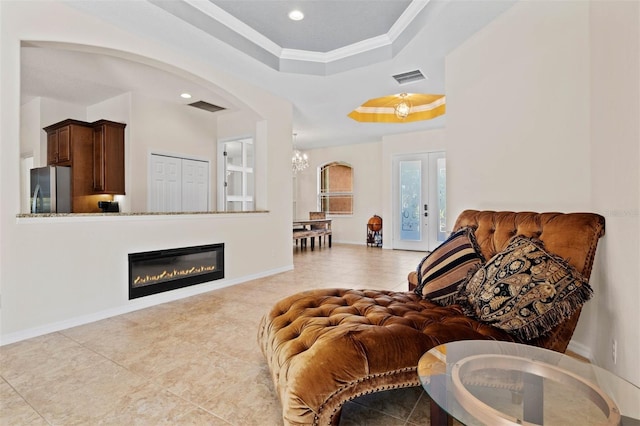 sitting room with french doors, ornamental molding, a tray ceiling, and light tile patterned flooring