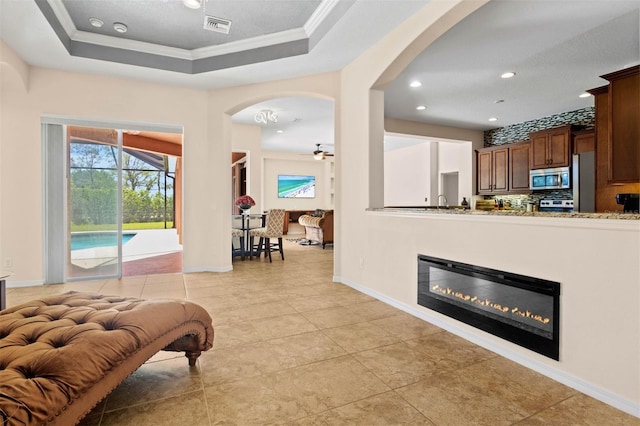 entryway with ornamental molding, a raised ceiling, ceiling fan, and light tile patterned flooring