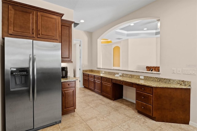 kitchen with light stone counters, a tray ceiling, and stainless steel fridge