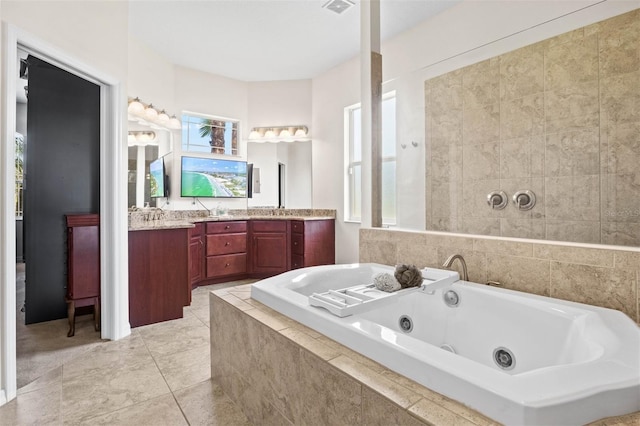 bathroom featuring tile patterned flooring, vanity, and tiled bath