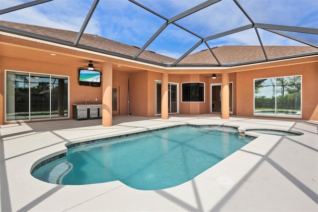 view of pool with glass enclosure, a patio, ceiling fan, and an in ground hot tub