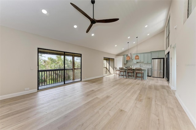 unfurnished living room with ceiling fan, high vaulted ceiling, and light wood-type flooring