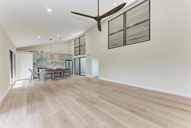 unfurnished living room featuring ceiling fan, high vaulted ceiling, and light hardwood / wood-style flooring