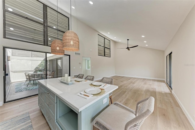 kitchen featuring ceiling fan, high vaulted ceiling, decorative light fixtures, and light hardwood / wood-style floors