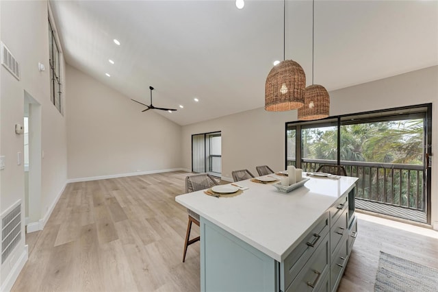 kitchen featuring decorative light fixtures, a center island, high vaulted ceiling, gray cabinets, and light hardwood / wood-style floors