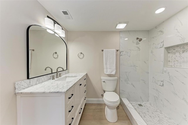 bathroom featuring vanity, hardwood / wood-style floors, toilet, and a tile shower