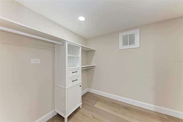 walk in closet with light hardwood / wood-style floors