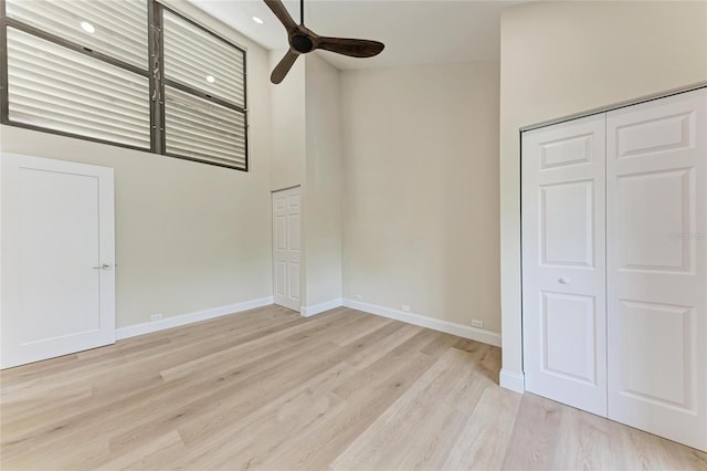 interior space with ceiling fan, light hardwood / wood-style floors, and a high ceiling