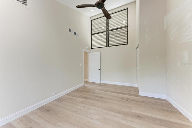 spare room with light hardwood / wood-style flooring, ceiling fan, and a high ceiling