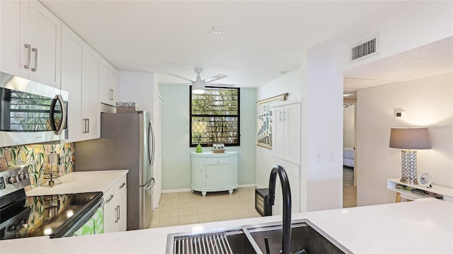 kitchen with light tile patterned floors, sink, ceiling fan, stainless steel appliances, and white cabinets