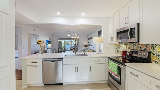 kitchen featuring sink, white cabinets, kitchen peninsula, stainless steel appliances, and an inviting chandelier