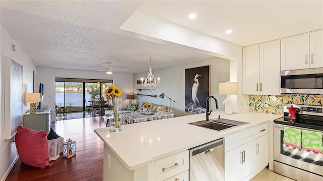 kitchen featuring sink, white cabinetry, kitchen peninsula, stainless steel appliances, and backsplash