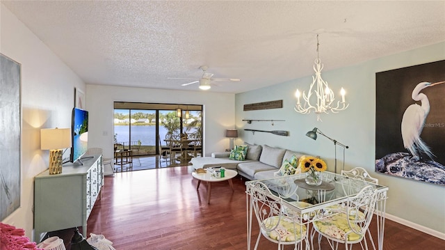 living room featuring dark hardwood / wood-style flooring, ceiling fan with notable chandelier, and a textured ceiling