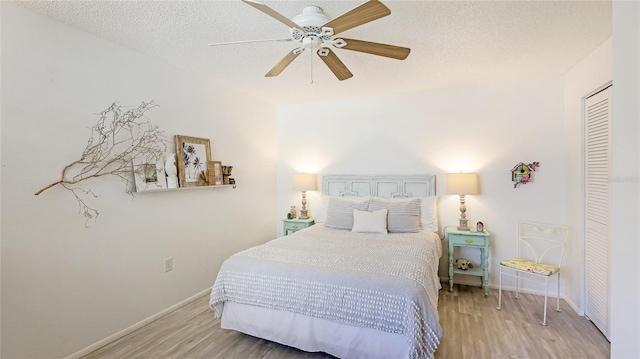 bedroom with ceiling fan, a closet, light hardwood / wood-style floors, and a textured ceiling