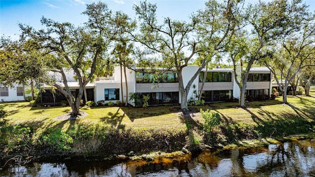 back of property featuring a water view and a lawn