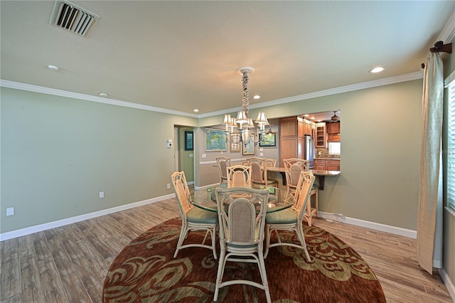 dining space featuring light wood-type flooring, visible vents, and baseboards