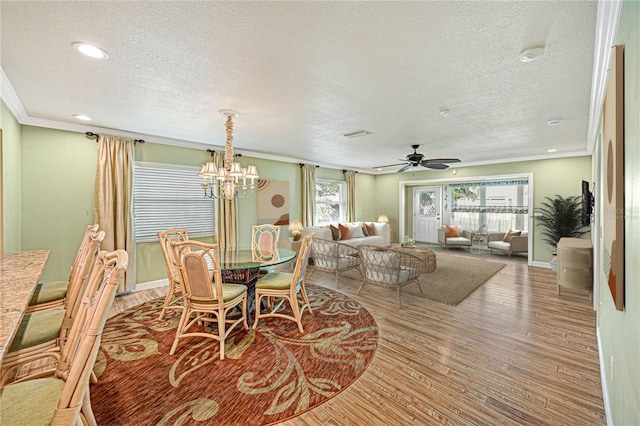 dining space featuring ceiling fan with notable chandelier, ornamental molding, hardwood / wood-style floors, and a textured ceiling